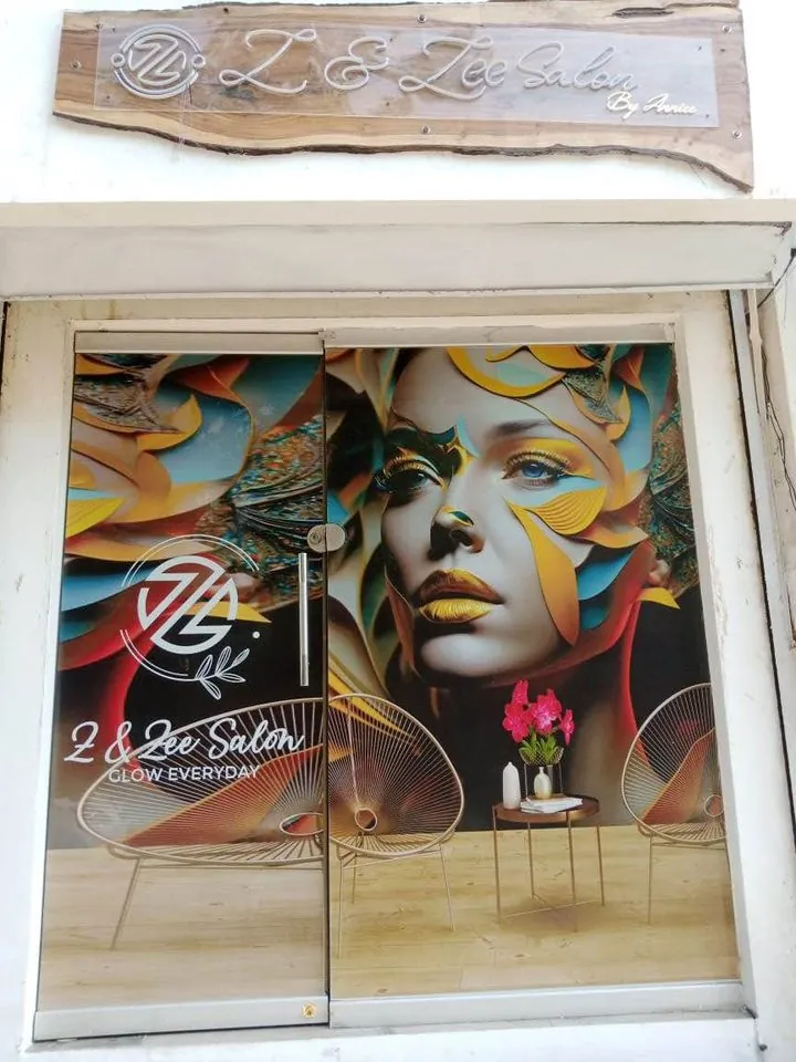 Z & Zee Salon storefront with a driftwood name sign and a gold-leaf portrait mural on the glass doors