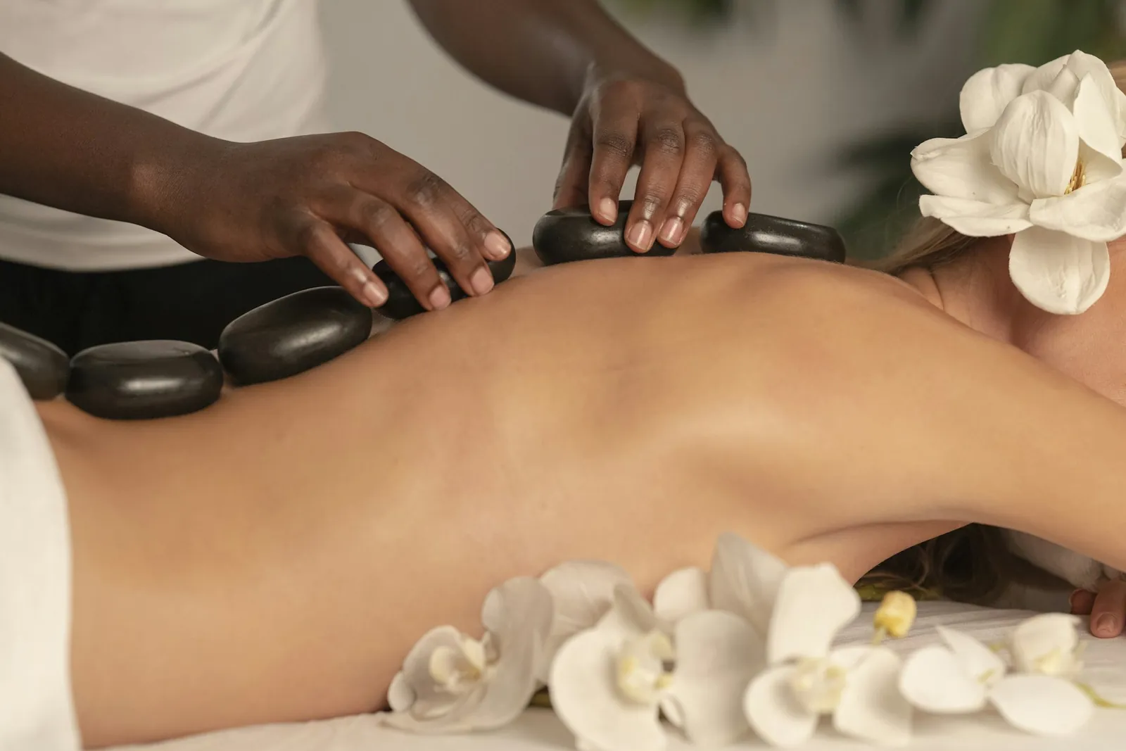 Therapist placing warm basalt stones along a client's back
